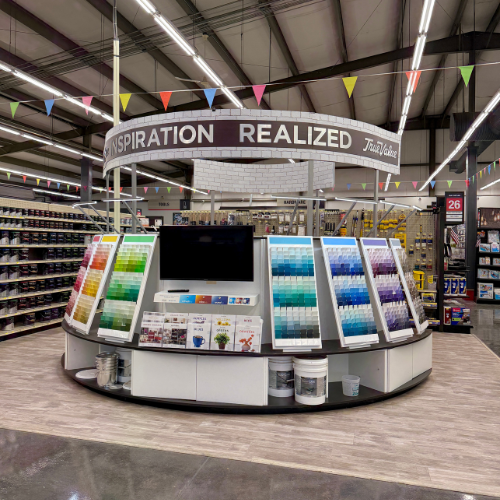 Display area with color swatches and a TV screen in a store setting, featuring 'Inspiration Realized' branding.