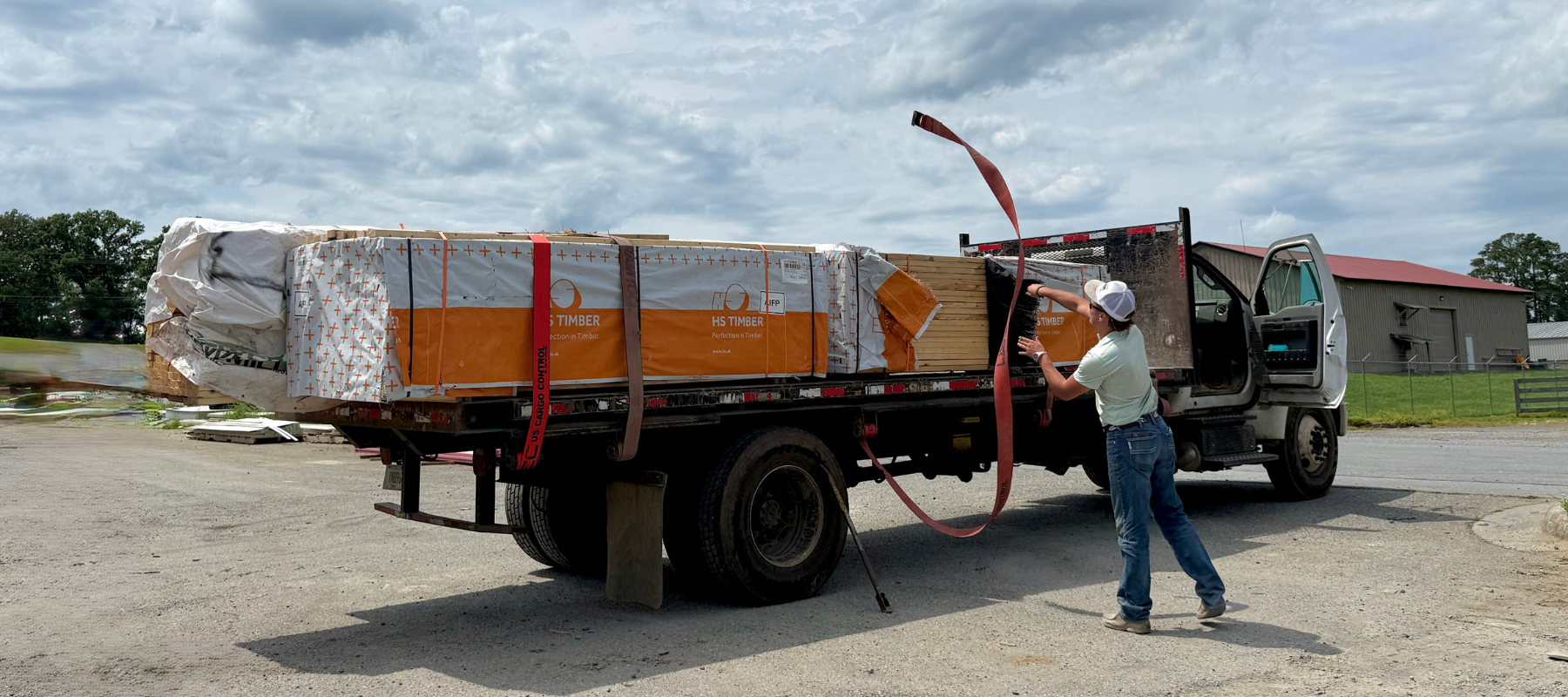 Person loading lumber on a truck on a sunny day.