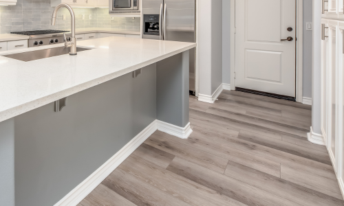 A white and gray kitchen surrounded with white moulding and trim