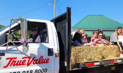 Kids on a hay bale on the back of a True Value truck